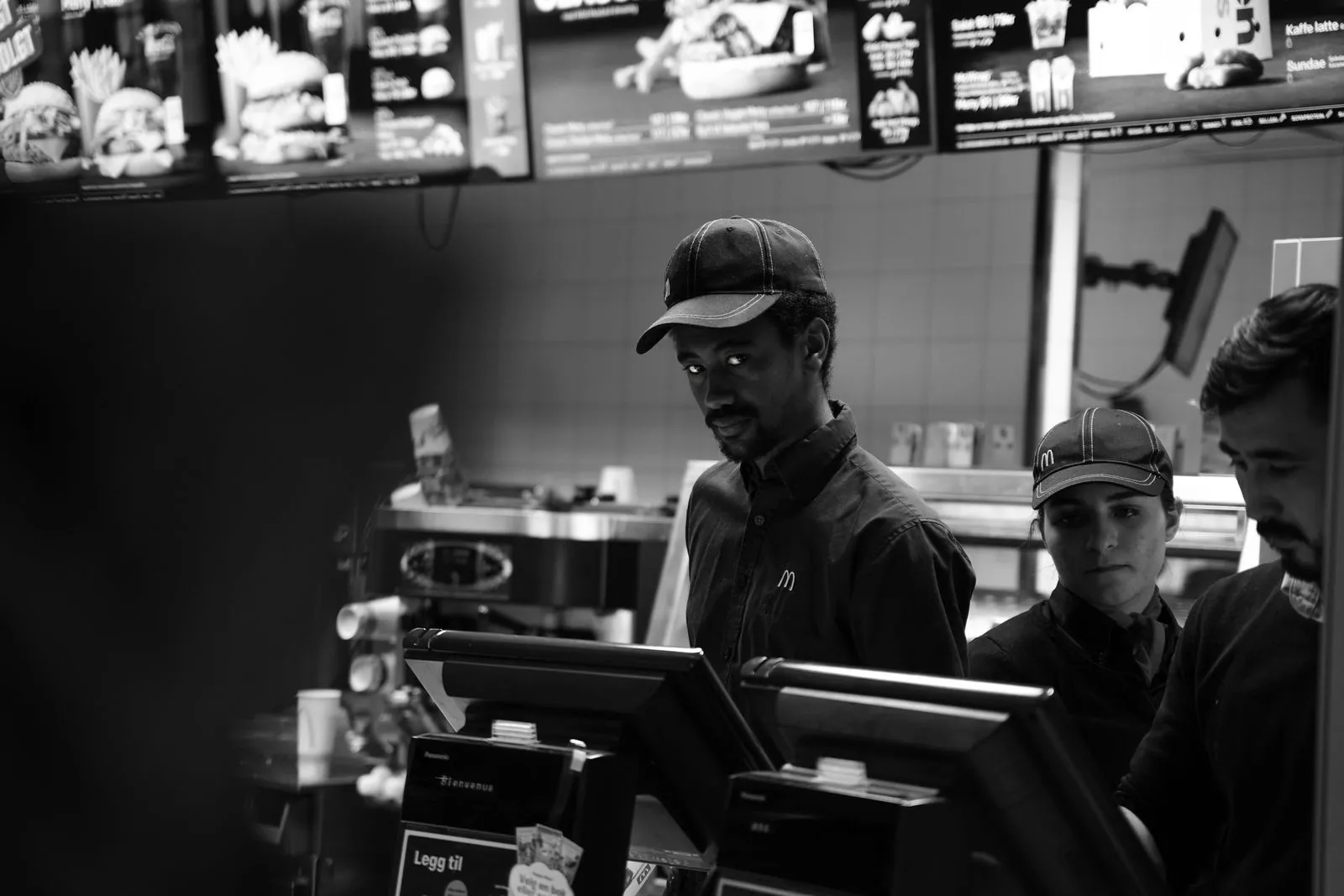 Black and white image of fast food employees behind the counter in Oslo, Norway.